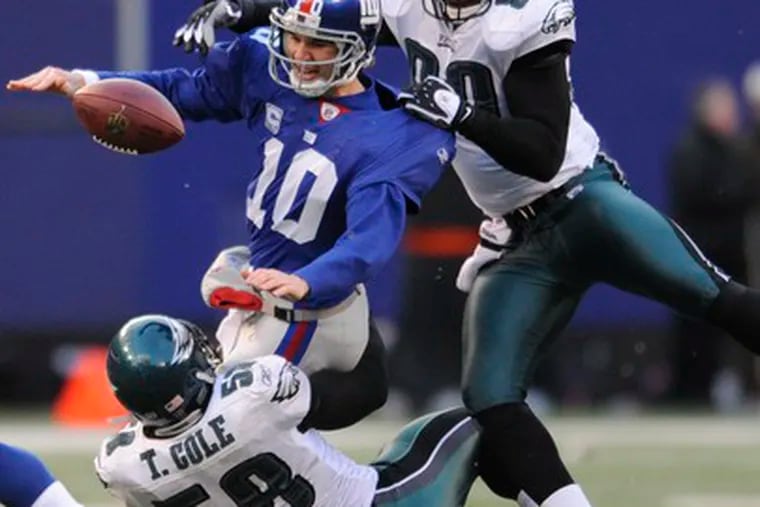 Eagles defensive linemen Trent Cole and Darren Howard keep Giants quarterback Eli Manning from converting on fourth down late in the fourth quarter.