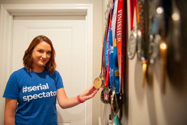 Shannon Connolly shows off the medals her wife won in races. Connolly's job was cheering, which has inspired her to start an apparel business catering to race spectators.