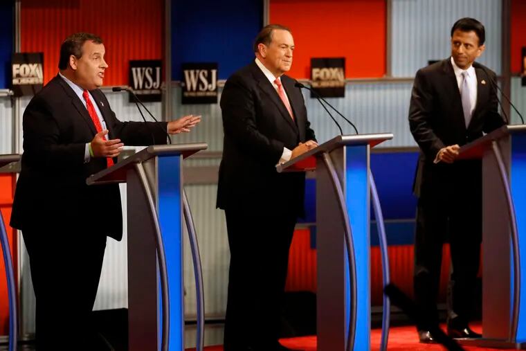 Gov. Christie (left) speaks as Mike Huckabee and Bobby Jindal listen during the Republican presidential debate Tuesday at the Milwaukee Theatre. Jindal criticized Christie's fiscal record as governor. AP