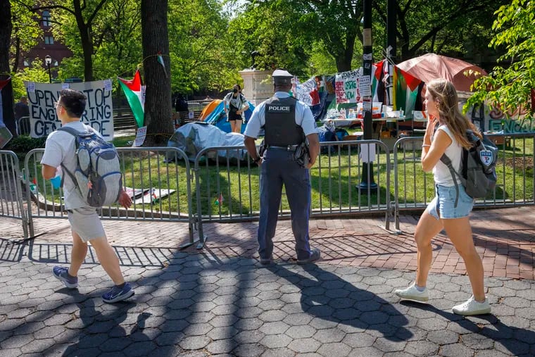 University of Pennsylvania police officer outside a pro- Palestine encampment as students cross campus on Monday.