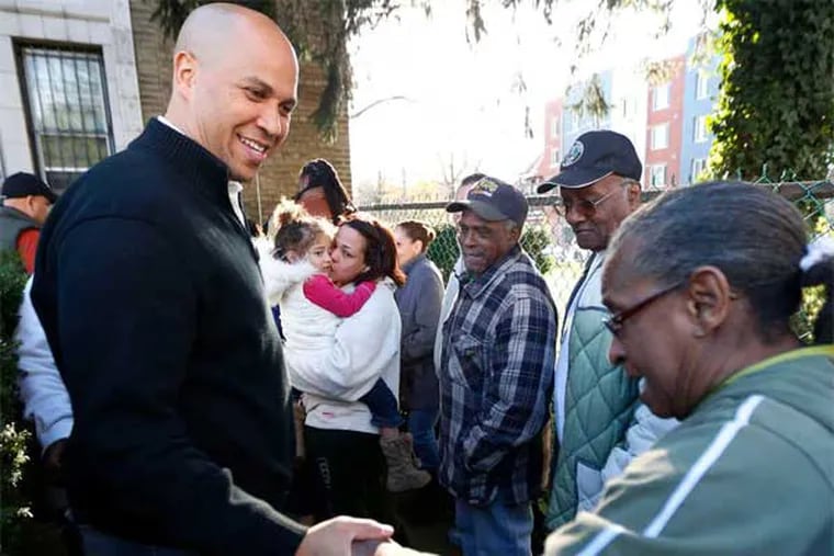 Newark, N.J., Mayor Cory Booker shakes hands with Grace Harris as she waits at a community center for donated clothing. (Julio Cortez / Associated Press)