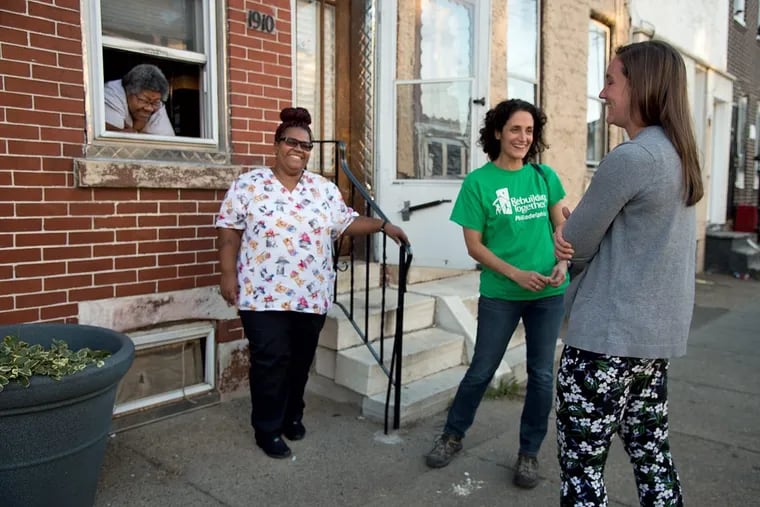 Elander Liles (left) and her mother Glander Liles (in the window) and Stefanie Seldin (second from right), executive director of Rebuilding Together Philadelphia and Tess Donie (right), associate community engagement director of New Kensington Community Development Corporation, chat outside the Liles’ Kensington home.