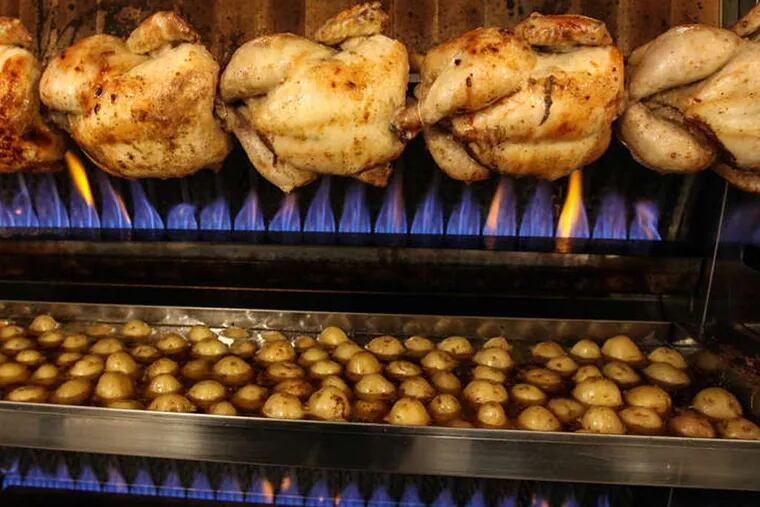 Chickens roasting on a spit, over a pan of potatoes, with the fire in the background, at Petit-Rôti. (STEVEN M. FALK / Staff Photographer )