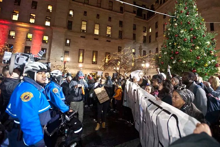 Police keep an eye on people protesting the death of Michael Brown during the 21st annual Christmas Tree lighting ceremony at City Hall. ( RON TARVER / Staff Photographer ) December 3, 2014