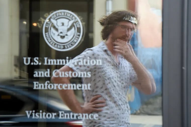 Wearing his ninja-style headband with the Naruto Leaf Village symbol, Jeremy Sims is reflected in the glass door of the the ICE Field Office on North 8th Street in Philadelphia. A self-professed geek working for a local arts non-profit, he was inspired by the viral "Storm Area 51" Facebook event and its use of the Naruto Run - a fictionalized anime running style - to organize his own protest against ICE on August 31.