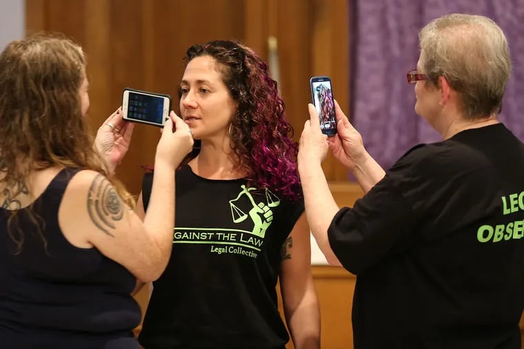 Aine Fox, left, and Jody Dodd, right, use phones to record during a role playing session with Amanda Spitfire, center, for those planning to protest during the Democratic National Convention later this month.