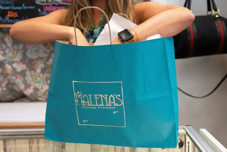 Malena Martinez, the owner of Malena's Vintage Boutique, fills a re-usable paper bag inside her store. The boutique has been plastic free for three years, an early adopter of the philosophy behind a new ban on single-use plastics in the borough.
