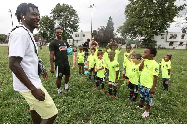 The Union's Olivier Mbaizo (left) and clinic coordinator Nick Bibbs talk with players 4 to 8 years old at a SWAG soccer clinic.