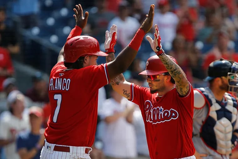 Maikel Franco (left) high fives teammate Freddy Galvis after Galvis hit a two-run home run/