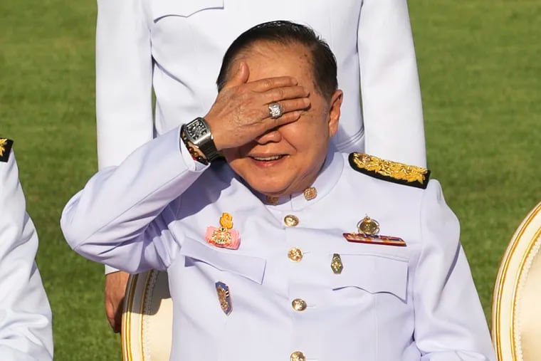 FILE - In this Dec. 4, 2017, file photo, Thailand's Deputy Prime Minister Prawit Wongsuwan raises his hand to shade his eyes from the sun while wearing a luxury watch and diamond ring during an official ceremony at the Government House. Thailand's National Anti-Corruption Commission has declared Prawit innocent of failing to declare his assets in a case that sparked a scandal when he was spotted wearing a number of luxury watches that he would not easily be able to afford on his government salary. (AP Photo/Krit Phromsakla Na Sakolnakorn, File)