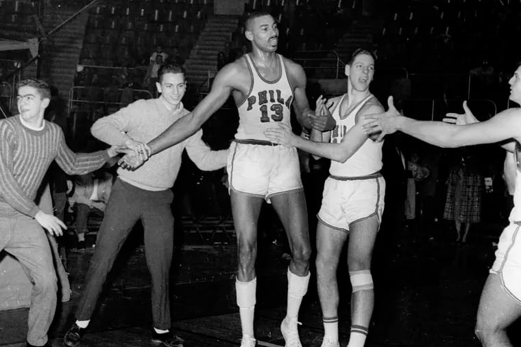 FILE - Fans and teammates rush onto court to congratulate Philadelphia Warriors Wilt Chamberlain (13) in Hershey, Pa., March 2, 1962, after he scored his 100th point in a win over the New York Knickerbockers. (AP Photo/Paul Vathis, File)