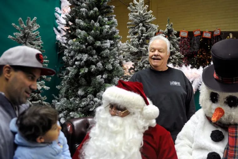 Ralph Gaudio (back), checks in on Santa and Frosty as Carlos Nieves and his 18-month-old son Carlos visit the Christmas Village in his Enchanted Land in South Philadelphia. ( TOM GRALISH / Staff Photographer )