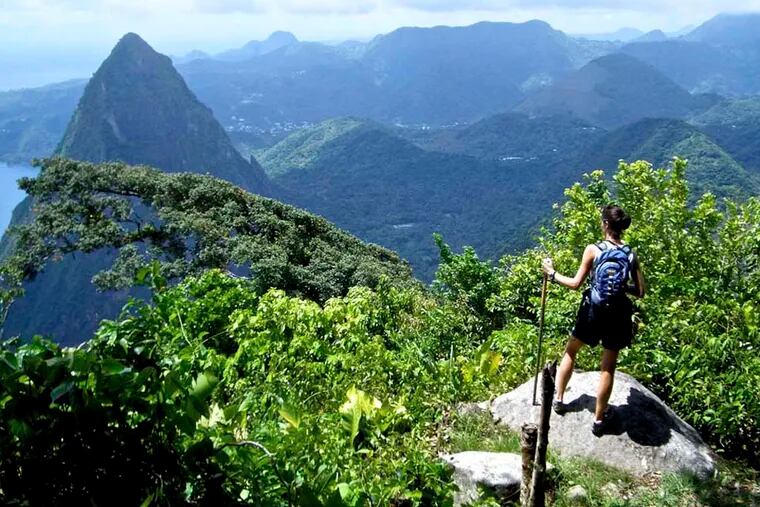 A hiker soaks in the view from atop Gros Piton, St. Lucia. (c) Amy Laughinghouse.