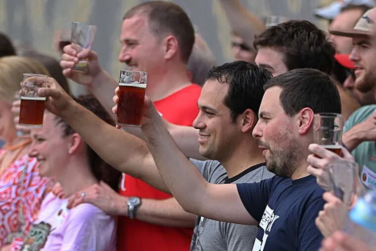 Rob Iocona (center) and Jeff Dodd (center right) raise glasses for a group photo outside Flying Fish Brewery. (Michael C. Bryant/Staff)