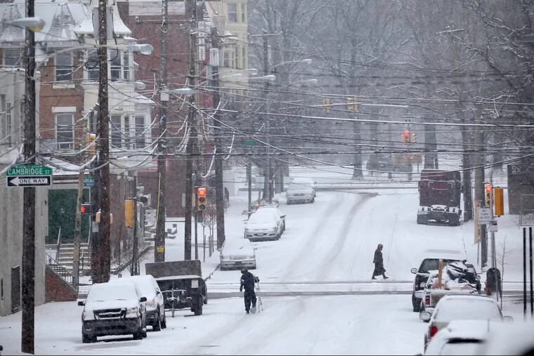 Pedestrians cross North 41st Street as snow falls in West Philadelphia on Saturday, Dec. 30, 2017.