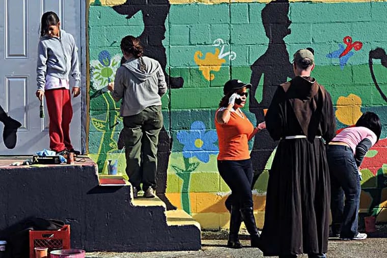 Father William 'Jud' Weiksnar looks over a mural being painted on a building by students at St. Anthony of Padua School in Camden last fall. He is leaving Camden after five years of advocacy on behalf of his students. ( RON TARVER / Staff Photographer ) July 08 2014