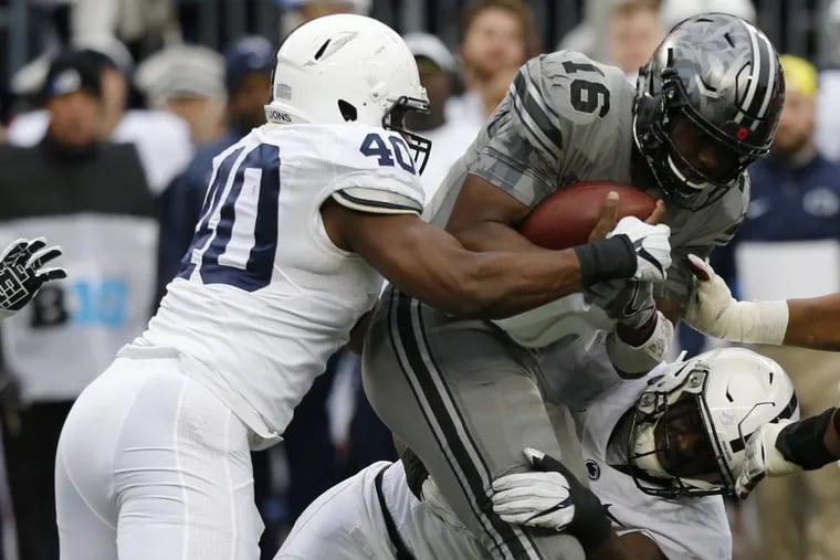 Ohio State quarterback J.T. Barrett  is sacked by  Jason Cabinda and Manny Bowen of Penn State.