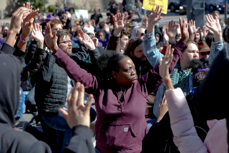 Marchers stop and sit with their hands up in an intersection in the streets in Pittsburgh Saturday during a protest.
