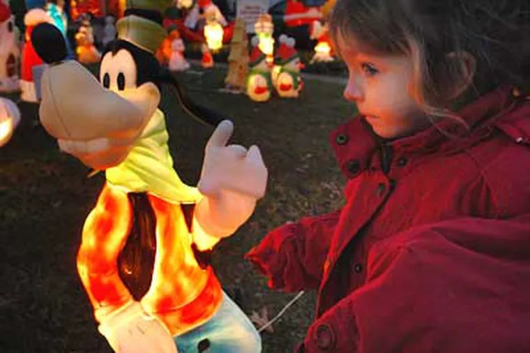 Kaitlyn Johnson gazes at Goofy and the other Christmas lights and characters at the Cherry Hill home of the Tinneny family. (Sharon Gekoski-Kimmel / Staff Photographer)
