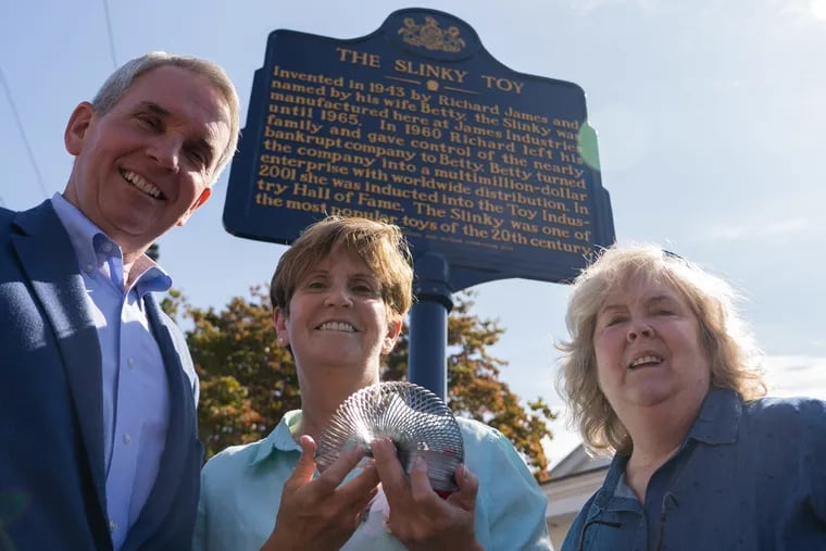 (From left to right) The children of the Slinky inventors, Christopher, Rebekah, and Elysabethe James, stand by the new Slinky Toy historical roadside marker outside the James Industries building on Baltimore Pike.