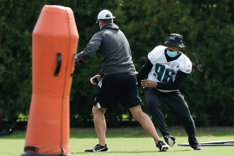 Eagles defensive end Derek Barnett (right) runs drills with a coach during training camp at the NovaCare Complex in South Philadelphia on Aug. 24. He is questionable for Sunday's opener at Washington.