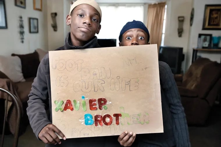 Xavier Johnson, 12, (left) and his brother Da'Shawn Johnson, 8, hold up some of their favorite artwork in the living room of their Phila. home on November 6, 2015. ( Elizabeth Robertson / STAFF PHOTOGRAPHER )
