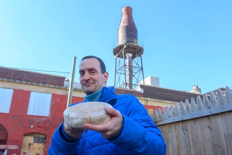 Cheese maker Yoav Perry, shows off a wheel of his washed rind Trappist-style cheese outside the old Harbison's Dairies building, where he hopes to open a shop. The building is currently undergoing renovations to turn it into residential and commercial space in the Kensington neighborhood of Philadelphia, January 29, 2020.