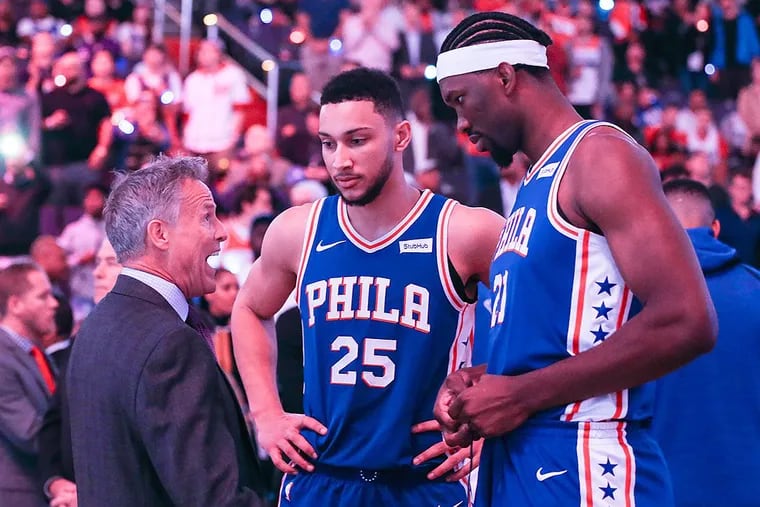 The Philadelphia 76ers’ Brett Brown talks with Ben Simmons (25) and Joel Embiid, right, before action against the Washington Wizards at the Capital One Arena in Washington, D.C., on Wednesday, Oct. 18, 2017. The Wizards won, 120-115.