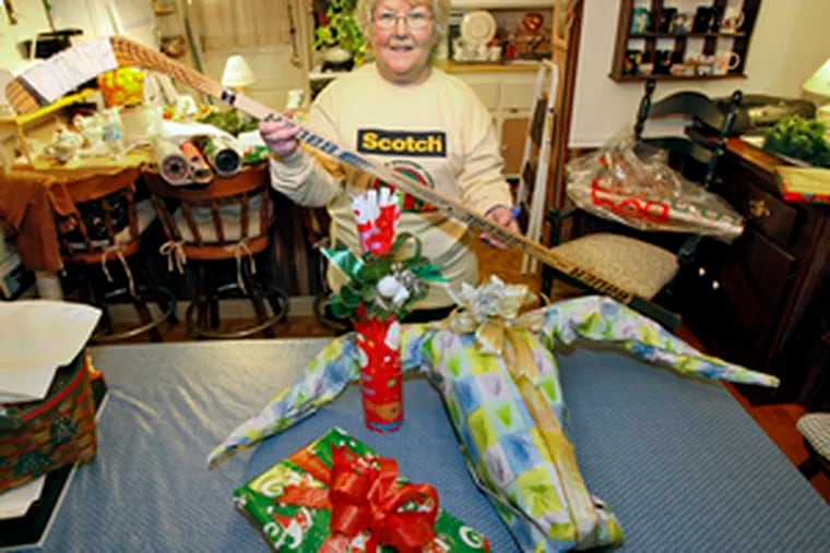 Janet Smith with several finished gifts and a hockey stick. To disguise it, she needed - but didn&#0039;t have - cardboard. &quot;Frankly, I don&#0039;t think it&#0039;s always important to disguise a gift,&quot; says the expert gift wrapper.