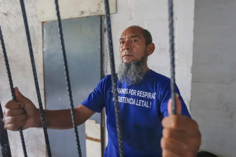 Alex Vanegas holds on to the iron bars he had installed on the porch of his apartment to symbolize his home arrest in Managua, Nicaragua, Tuesday, March 5, 2019. Grasping the iron bars, Vanegas is taken back to the dark prison cells where he spent the previous four months talking to fellow inmates through holes in the walls that also let in rats, scorpions and cockroaches, arrested for protesting against the government of President Daniel Ortega. (AP Photo/Alfredo Zuniga)
