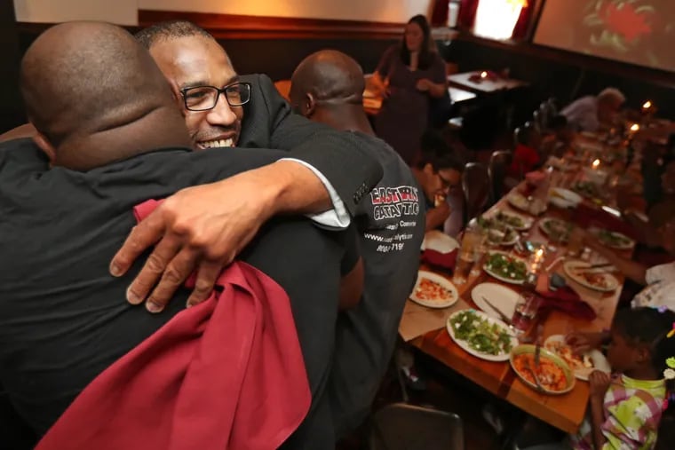 Anthony Wright gets a hug from Steve Waddell, left, at a family celebration at a South Street pizzeria in Philadelphia just hours after Wright was released in August 2016. 