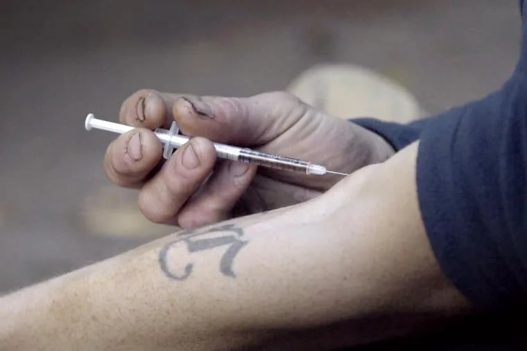 A heroin addict injects the drug.