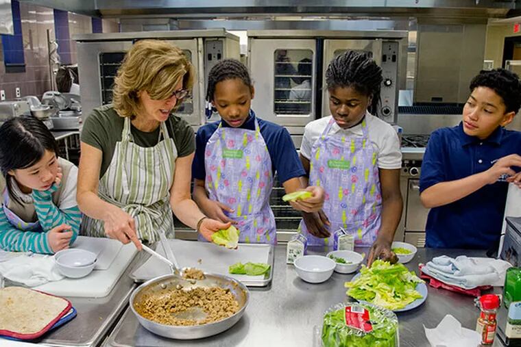 Inquirer food editor Maureen Fitzgerald demonstrates how to assemble a turkey lettuce wrap to Henry Lawton Elementary School fifth grade students Kimberly Luu, Nysirah Hall, Aneza Abalo and Nicholas Rodriguez.  ( CLEM MURRAY / Staff Photographer )