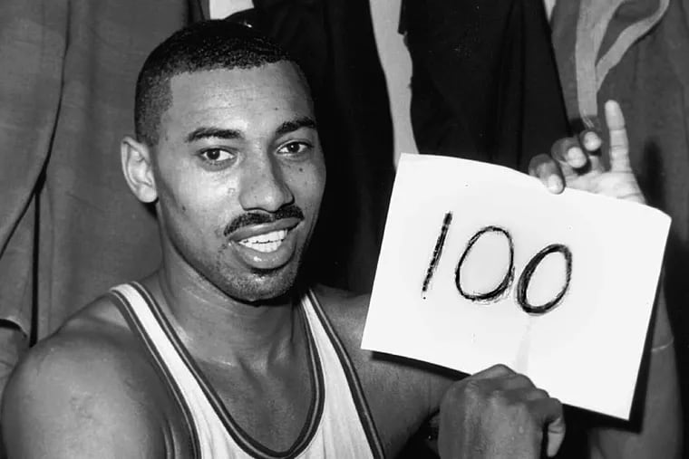 Wilt Chamberlain, of the Philadelphia Warriors, holding a sign reading "100" in the dressing room in Hershey, Pa., on March 2, 1962, after he scored 100 points as the Warriors defeated the New York Knickerbockers.