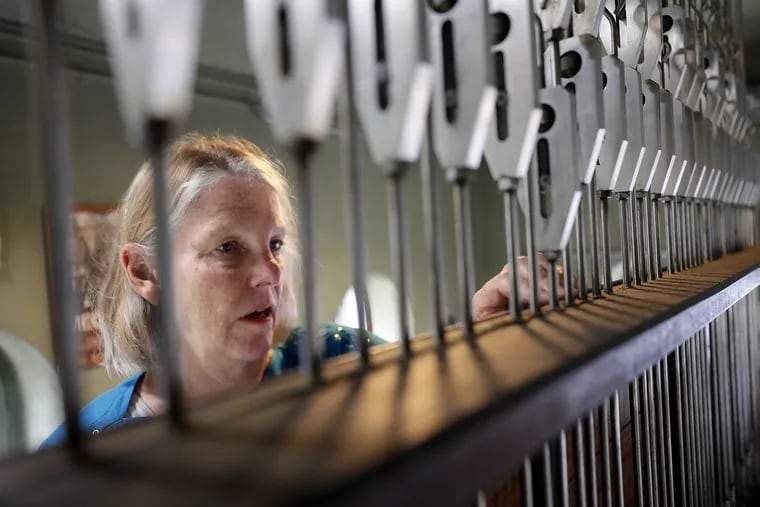 Janet Tebbel adjusts the cables to the carillon bells at the Miraculous Medal Shrine in Philadelphia.