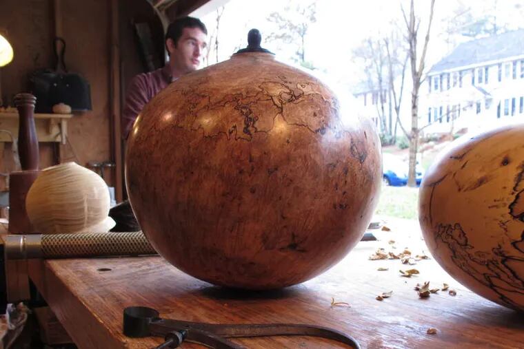 Two finished funerary urns, far left, by woodturner Jason Van Duyn sit in his Raleigh, N.C., studio. He is competing in a national urn show next month.