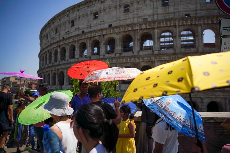Tourists hold umbrellas to shelter from the sun as they walk past the Colosseum, in Rome, during last week's incredible European heat wave.