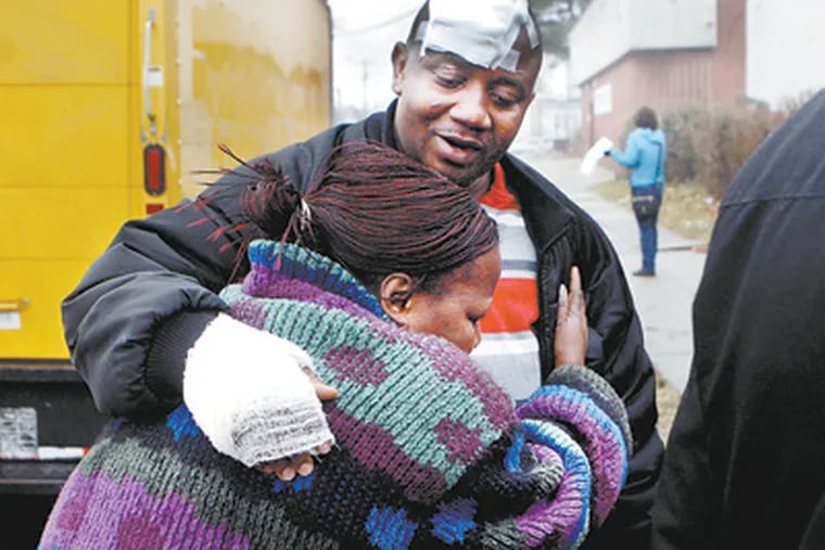 Harris Murphy comforts Christiana Teah outside the house in Southwest Philadelphia where seven died in a fire Friday night. Officials said the blaze began in the basement at 6418 Elmwood Ave. when a portable heater ignited as it was being filled with kerosene or gasoline. (Bonnie Weller / Staff Photographer)