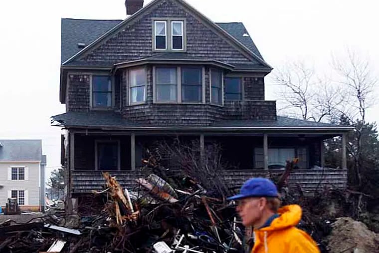 A resident of the Borough of Mantoloking in Ocean County, New Jersey walks past a home with debris from Hurricane Sandy on Sunday, December 17, 2012.  ( Yong Kim / Staff Photographer )
NJXMANT18C