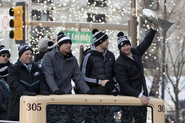 Philadelphia Eagles NFL football team quarterback Carson Wentz, right, holds up the Vince Lombardi trophy as he rides with fellow quarterbacks Nate Sudfeld, center right, Nick Foles, center left, and team owner Jeffrey Lurie, left, during a Super Bowl victory parade, Thursday, Feb. 8, 2018, in Philadelphia. The Eagles beat the New England Patriots 41-33 in Super Bowl 52.