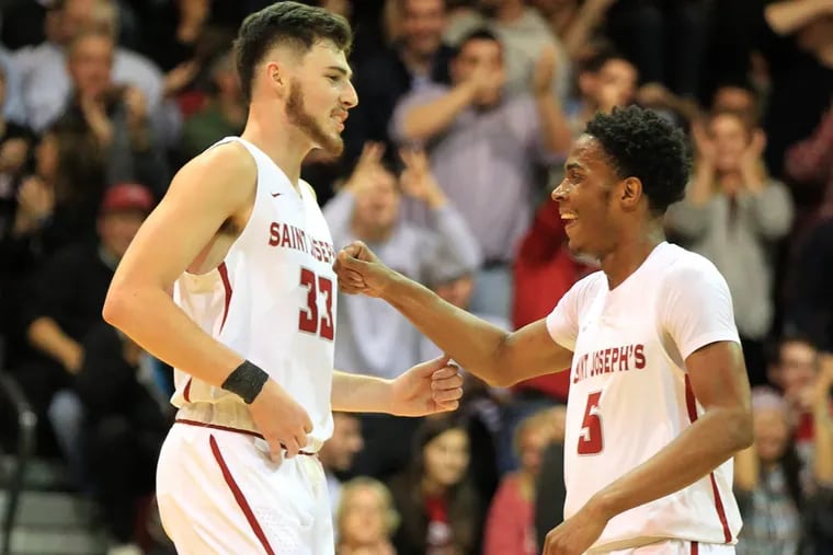 Taylor Funk, left, of St. Joseph’s celebrates with teammate Nick Robinson after Funk hit a three-pointer against Princeton.