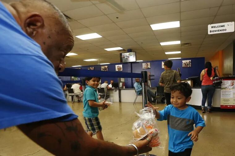 Volunteer Monroy Martinez, left, hands out a free to-go lunch to a young boy at the St. Mary's Food Bank Alliance in Phoenix.