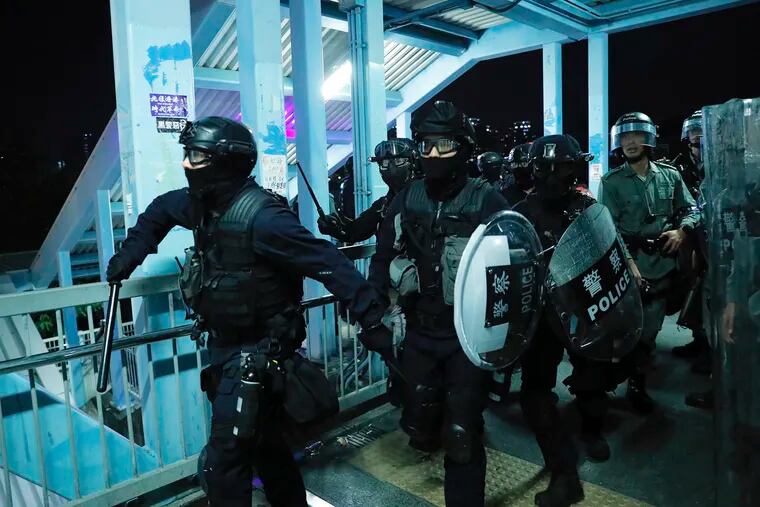 Riot police gather outside the Yuen Long MTR station during a protest in Hong Kong, Wednesday, Aug. 21, 2019.  Hong Kong riot police faced off with protesters occupying a suburban train station Wednesday evening following a commemoration of a violent attack there by masked assailants on supporters of the anti-government movement.