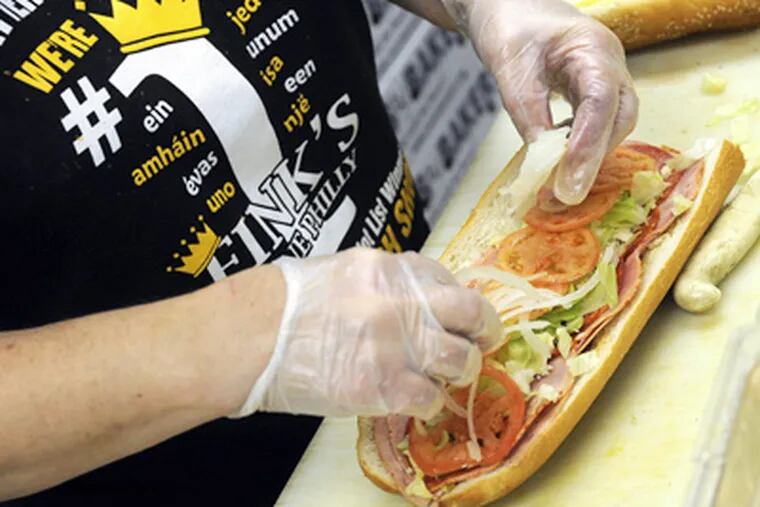 Karen Williams prepares a hoagie at Fink's in Tacony, one of the shops listed in the "hoagie finder." (Tom Gralish / Staff Photographer)