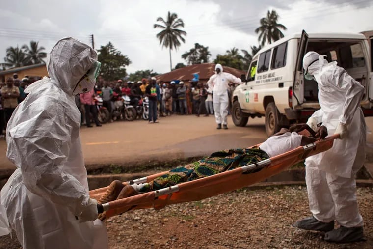 Workers in protective gear load a man believed to have Ebola onto an ambulance in Kenema, Sierra Leone. Last week, two men from Sierra Leone visited a New Jersey relief office with grim reports on the virus that has killed 3.400 in West Africa. (TANYA BINDRA / Associated Press)