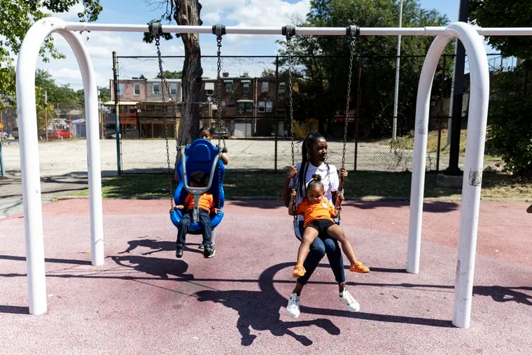Shahira Davis, owner of Little Scholars of the Future Learning Academy, is on the swing with one of the kids at her day care in Philadelphia.
