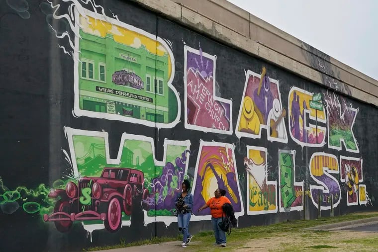 Two women walk past a mural in Tulsa, Okla., commemorating Black Wall Street, which was destroyed by a white mob in 1921. Creating more economic opportunities for Black Americans is an unfulfilled aspect of emancipation, writes Chad Dion Lassiter.
