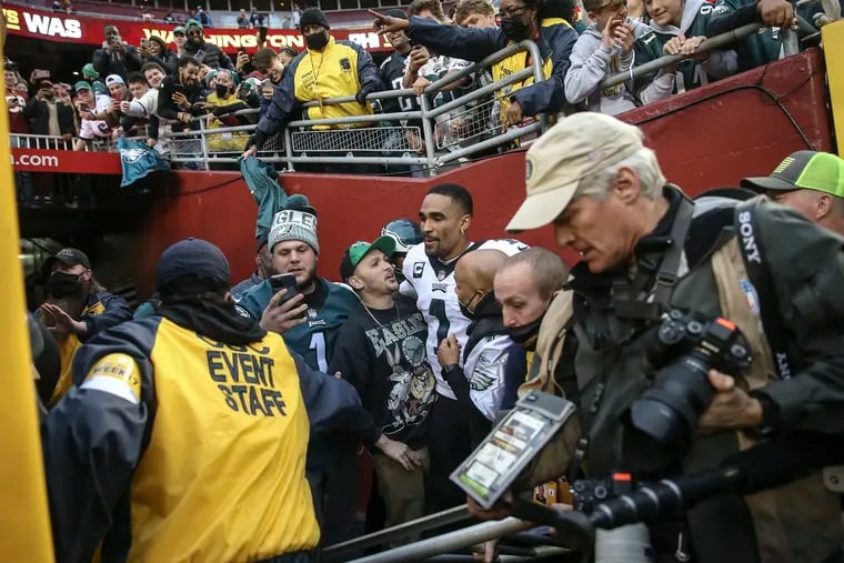 Fans surround Eagles quarterback Jalen Hurts after a railing gave way into the Eagles tunnel, injuring a photographer and a youngster after the game at FedEx Field.