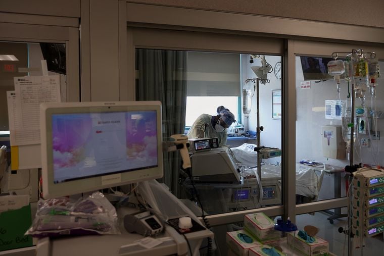 A medical worker works inside a patient room in a COVID-19 intensive care unit at Temple University Hospital's Boyer Pavilion in April.