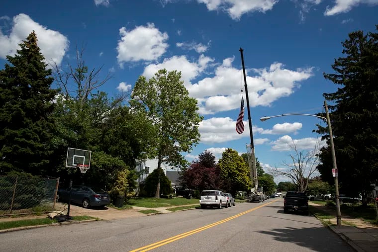 An American flag on a crane flies over the home of Michael Santucci, 60, on the day he was released from the hospital after a long stay because of COVID-19 in the Fox Chase section of Philadelphia, Pa. on Wednesday, June 23, 2021. Santucci's son-in-law Joe Pace hired the crane to welcome him home.